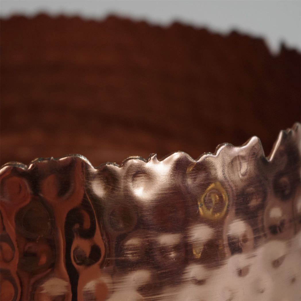 Close-up of scalloped edge and hammered texture on copper planter.
