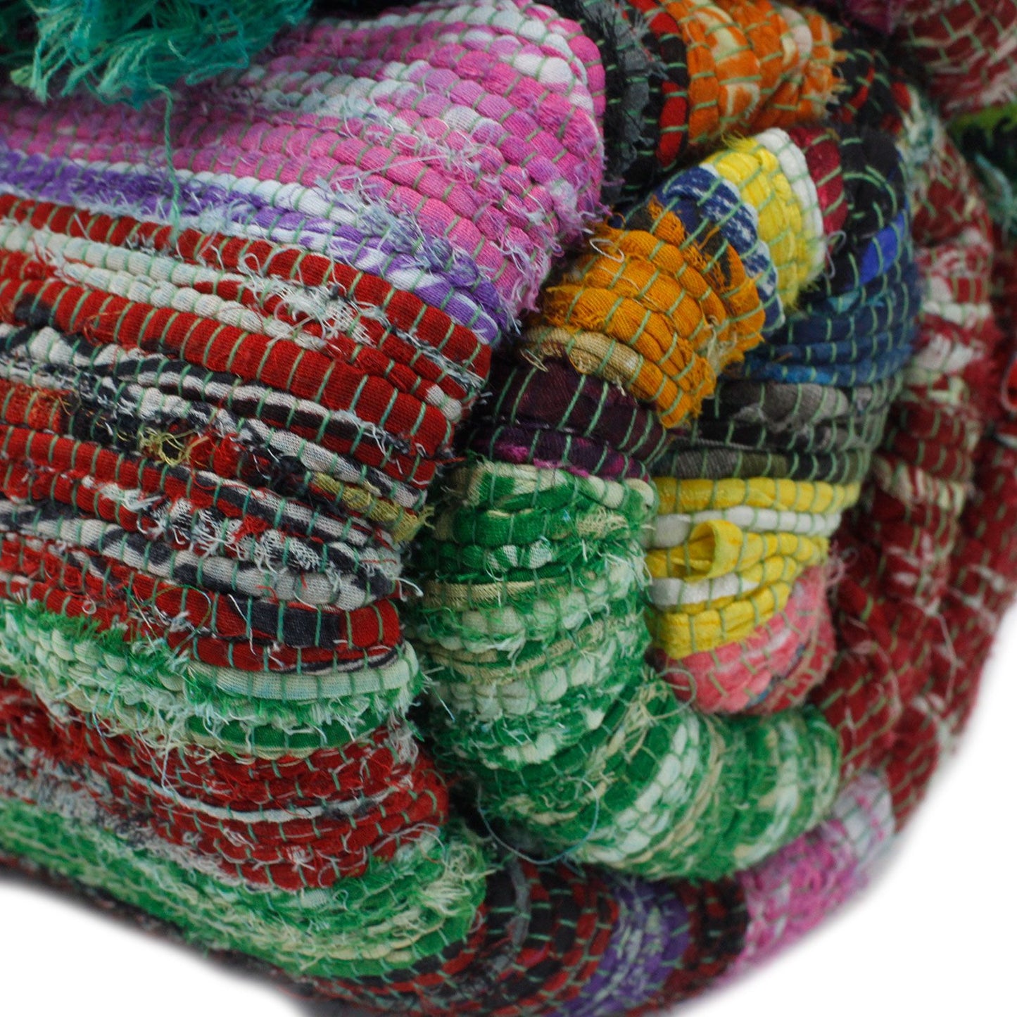 Rolled-up recycled rag rug displaying colourful bands of fabric in green, pink, red, and yellow.
