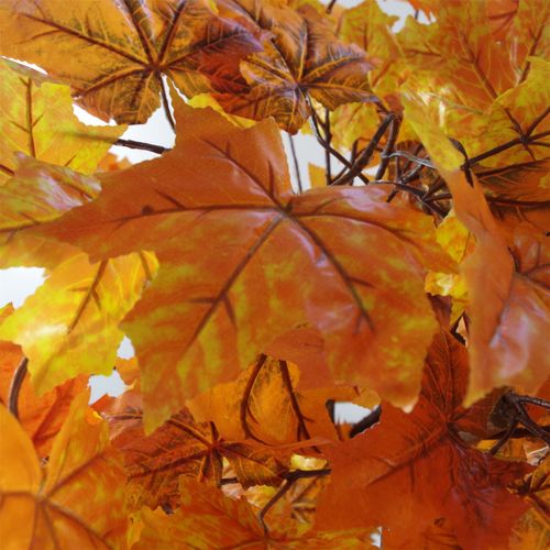 Detailed view of textured plastic maple leaves on artificial tree.