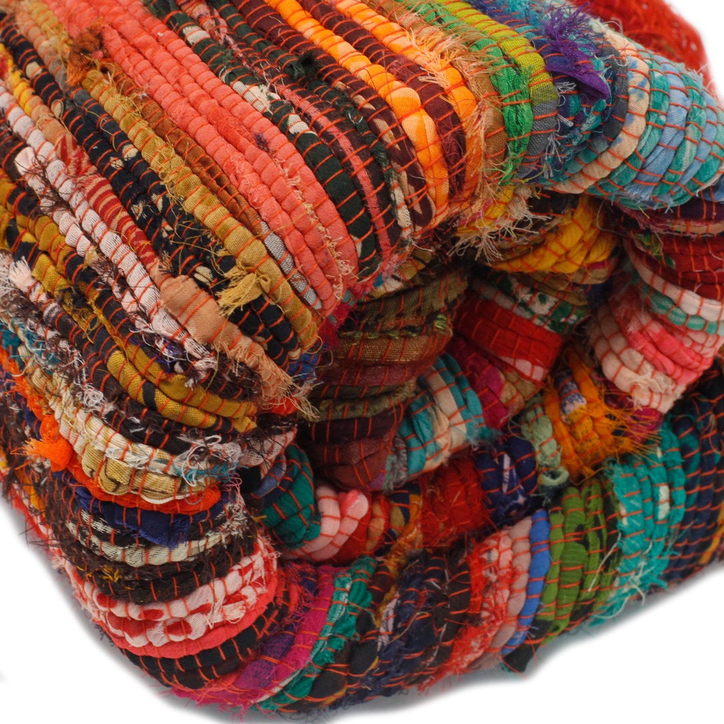 Close-up of rolled multicoloured orange rag rug showing soft cotton texture and frayed edges.