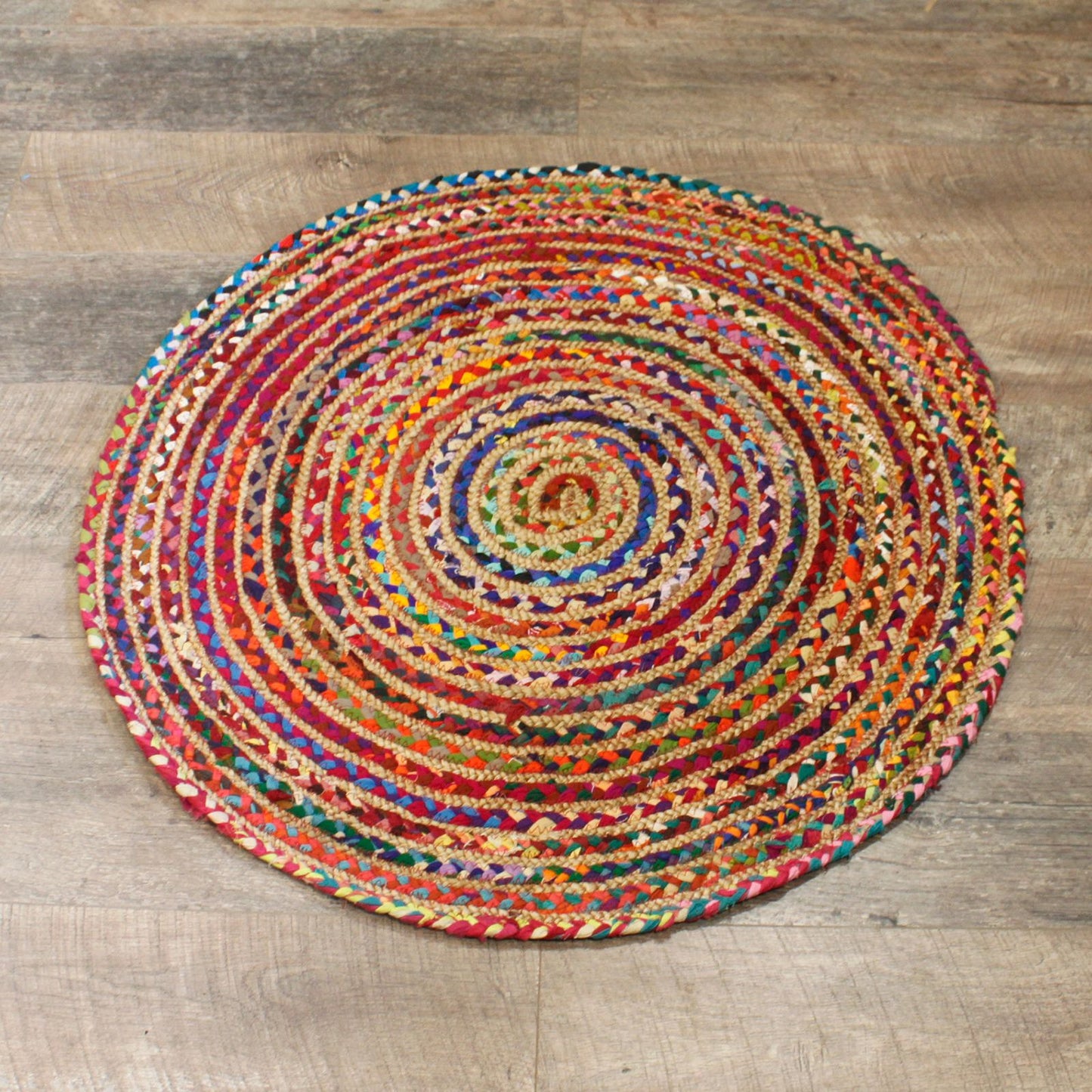 Overhead view of a vibrant handmade round rug with red, gold, and purple tones.