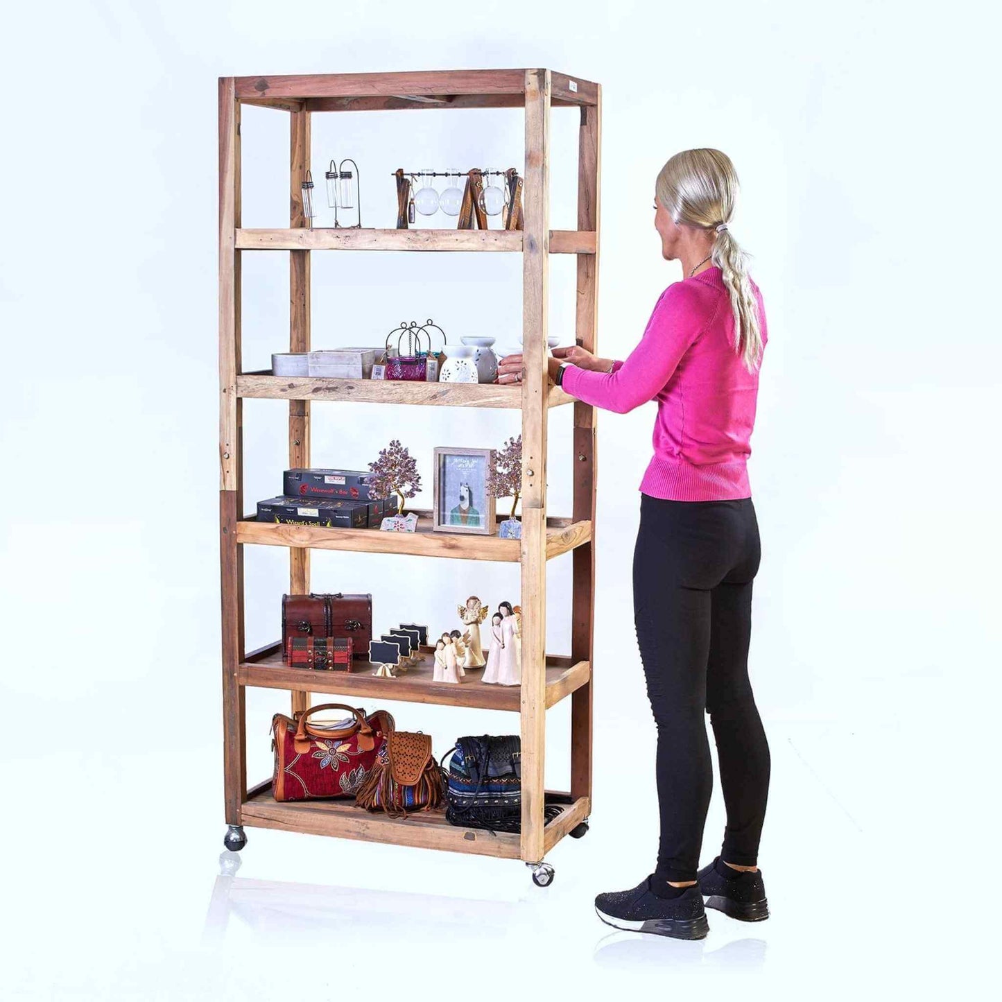 Six-shelf display unit made from recycled teak wood with casters, shown with a blonde woman styling accessories.