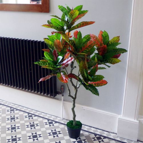 Artificial Codiaeum tree in black plastic pot with vibrant variegated leaves.