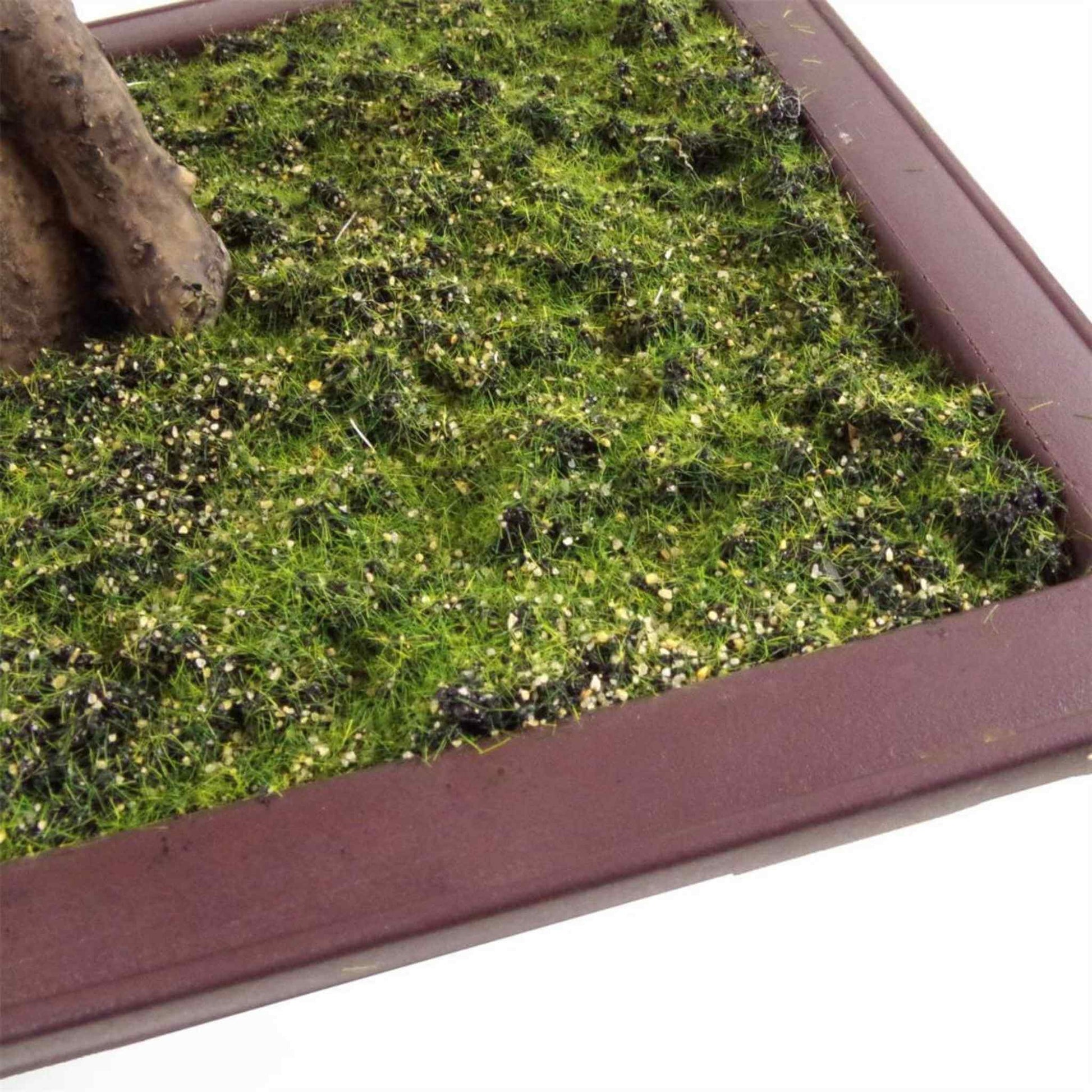 Moss-effect base detail in brown planter beneath artificial bonsai tree.