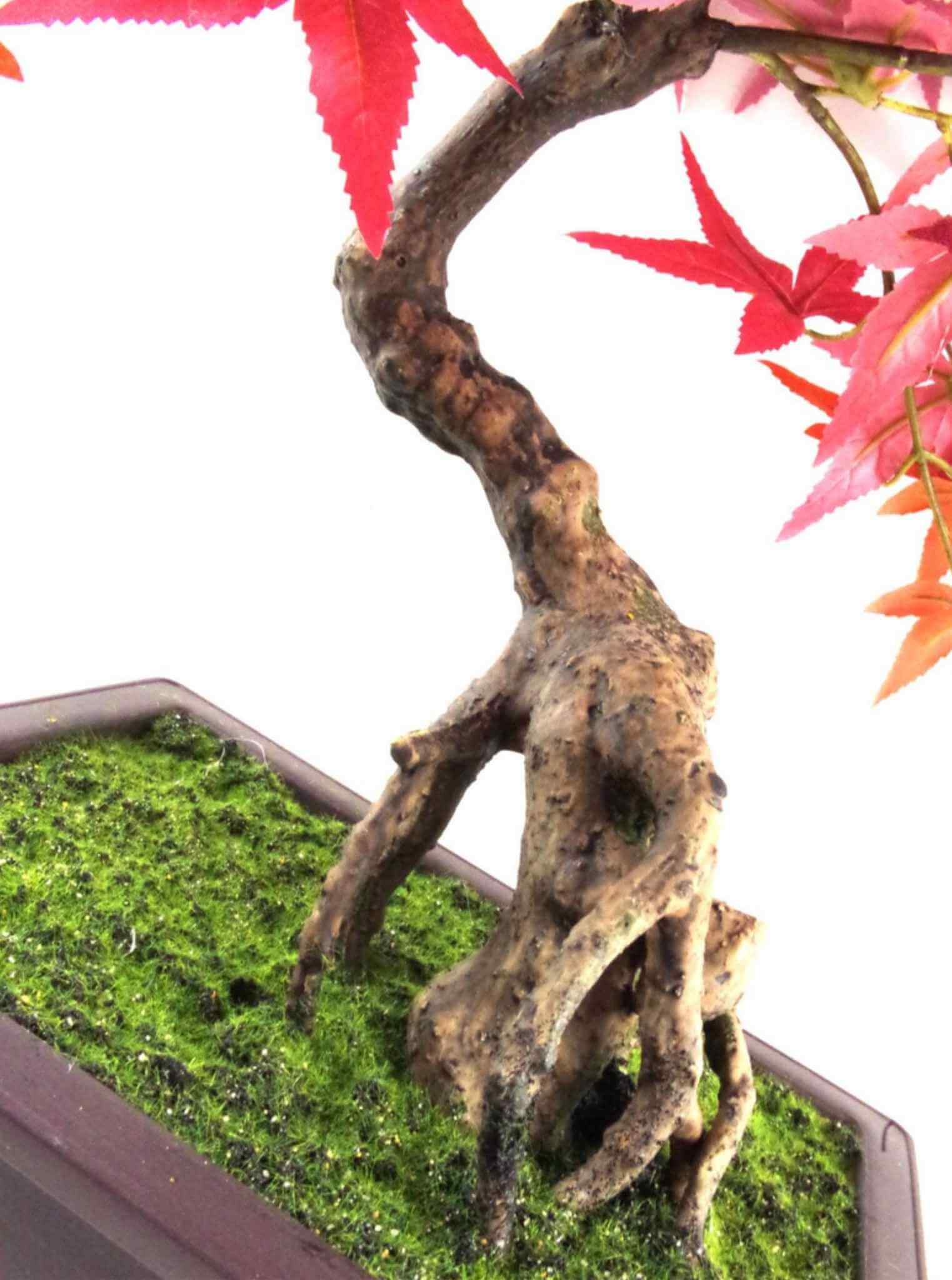 Close-up of artificial bonsai trunk detail with natural texture, rising from a moss-effect base.