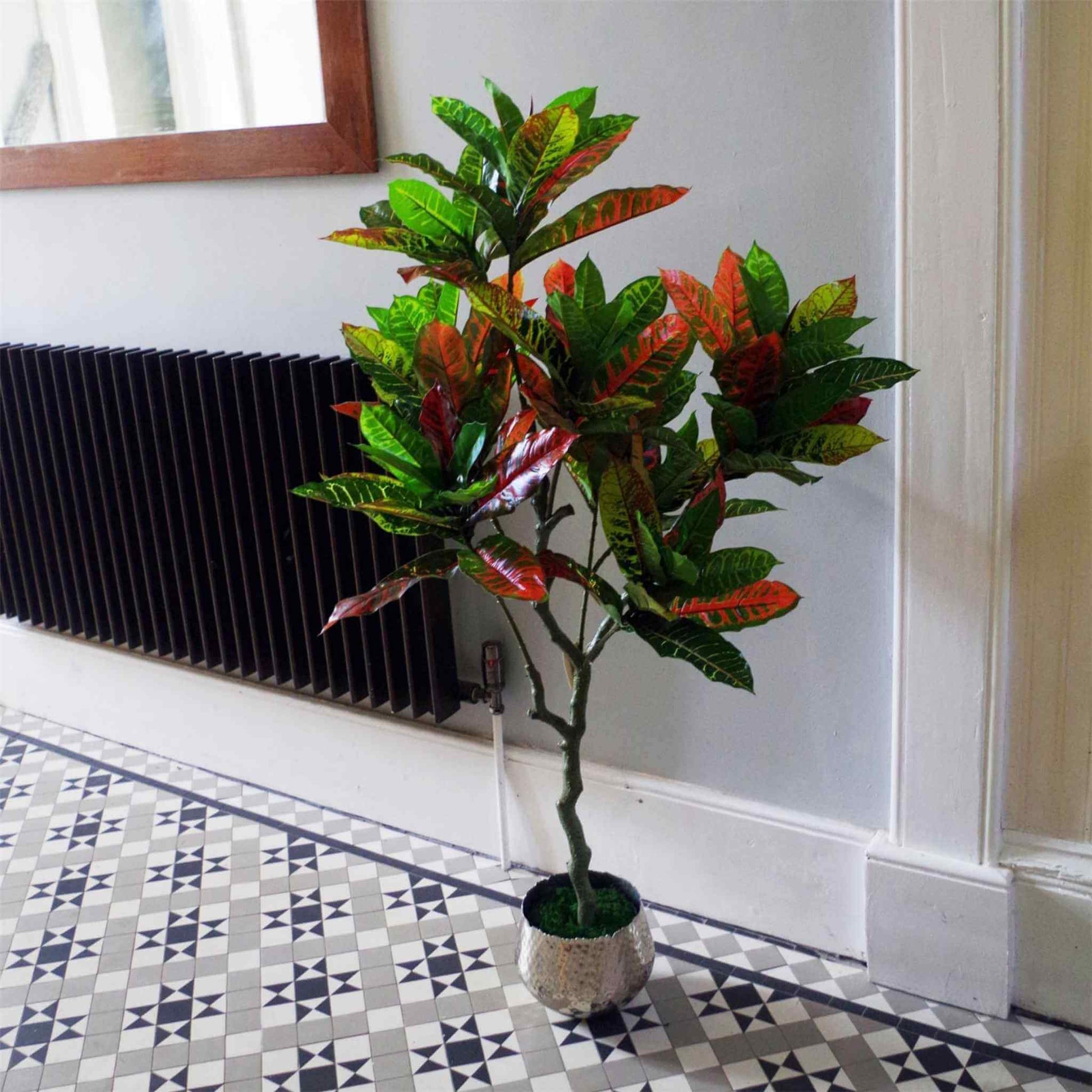 130cm artificial Codiaeum tree in a decorative silver planter, styled by a hallway radiator and mirror.