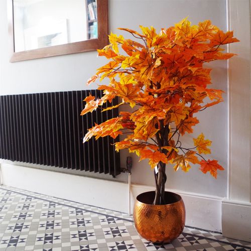 125cm artificial orange maple tree in a copper planter placed beside a radiator on a tiled hallway floor.