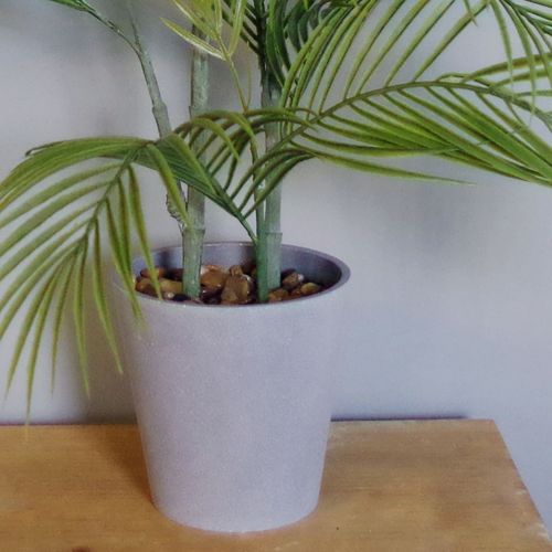 Close-up of the decorative grey planter base with fixed pebbles for the 90cm artificial palm tree.