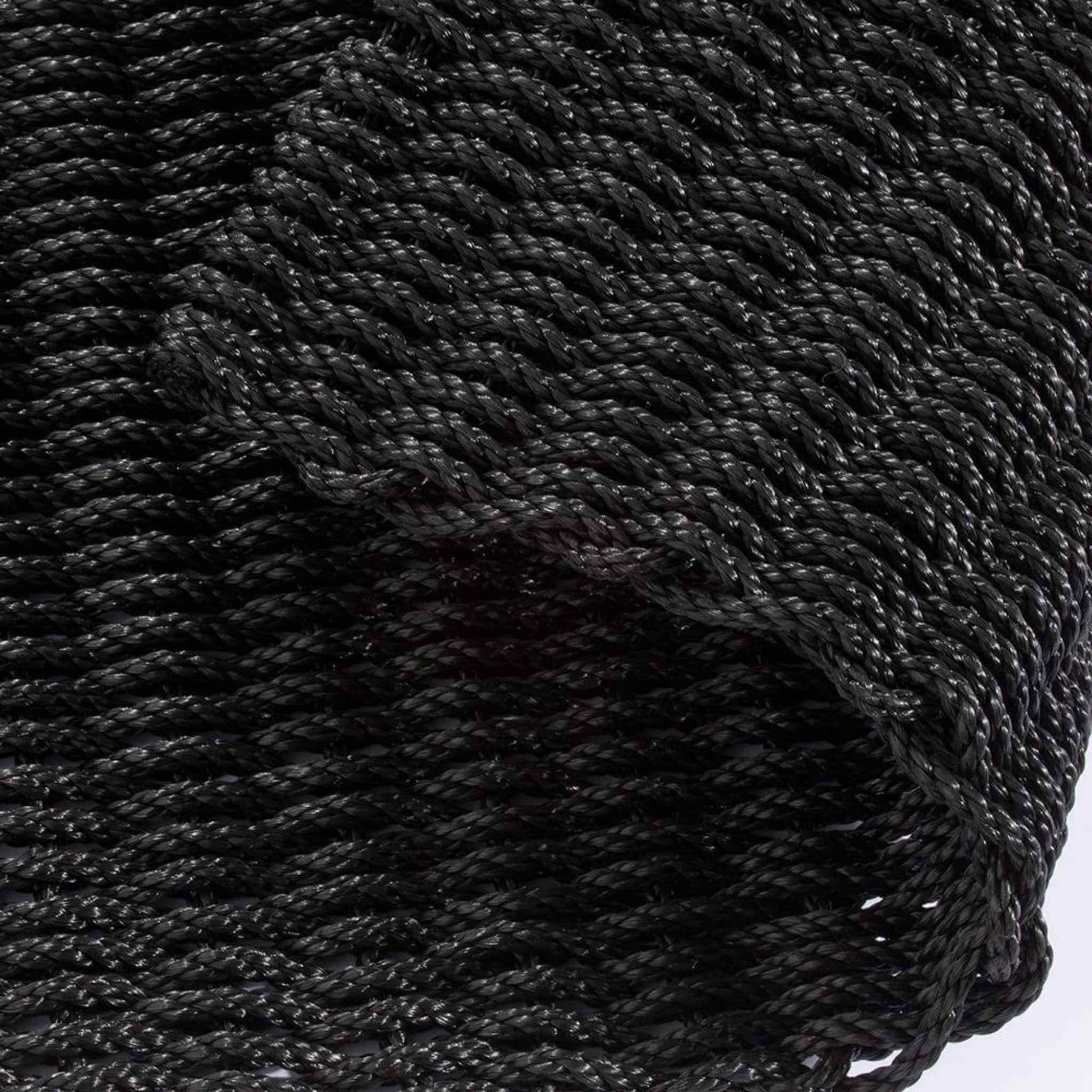 Folded view of charcoal braided polypropylene doormat showing flexible, thick weave structure.