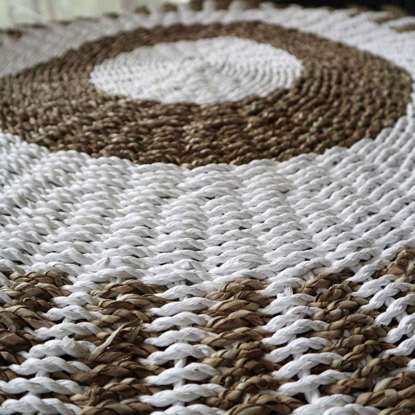 Close-up detail of hand-woven seagrass texture showing white and tan circular pattern.