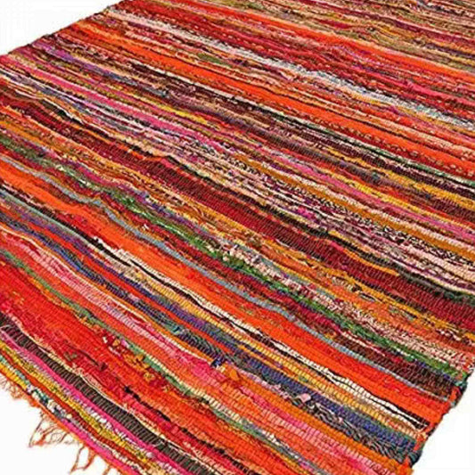 Luxury Indian rag rug 150x90cm with orange fringe and colourful striped weave, laid flat on the floor.