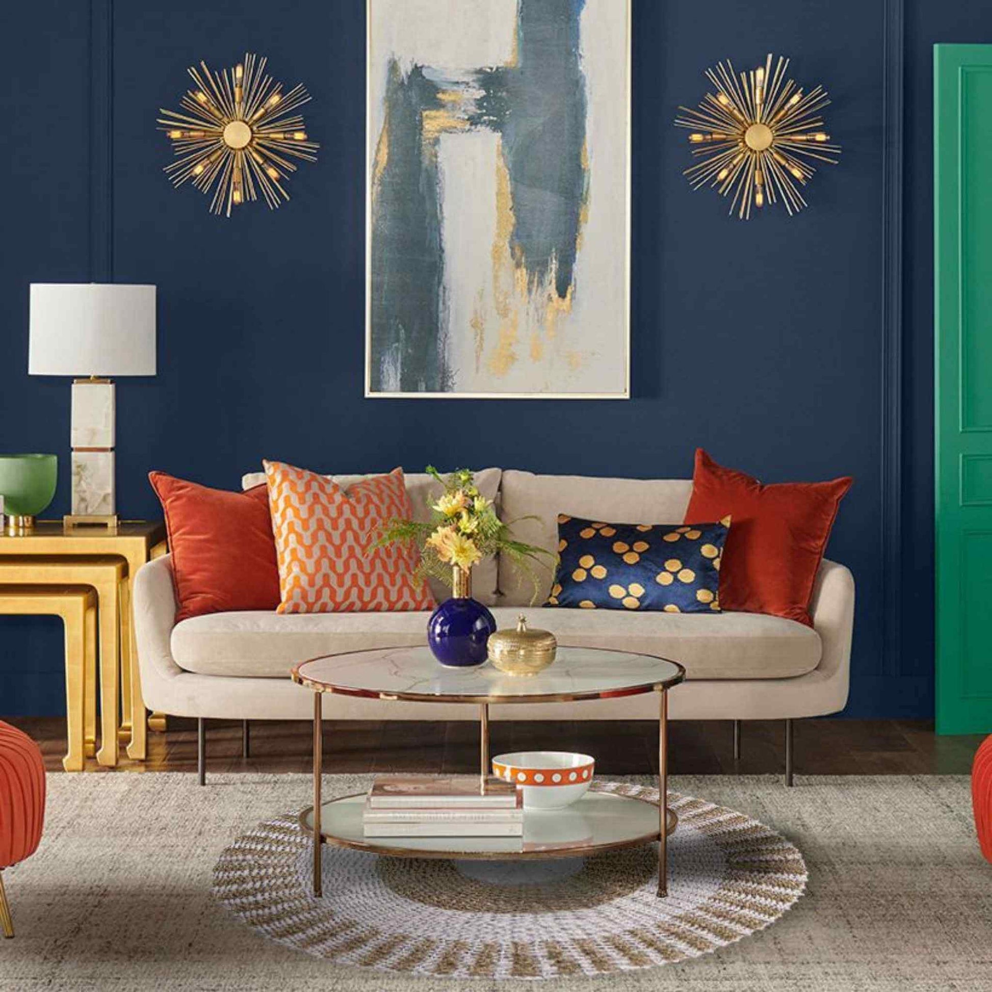 Round, white and tan seagrass rug styled under a glass coffee table in a cosy living room with bold cushions and a navy wall.