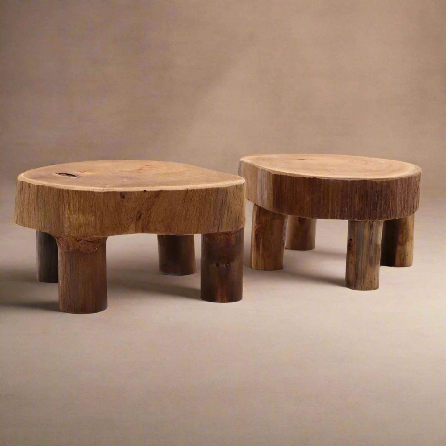 Pair of low round teak display stands on a beige background, highlighting natural wood grain and cylindrical legs.