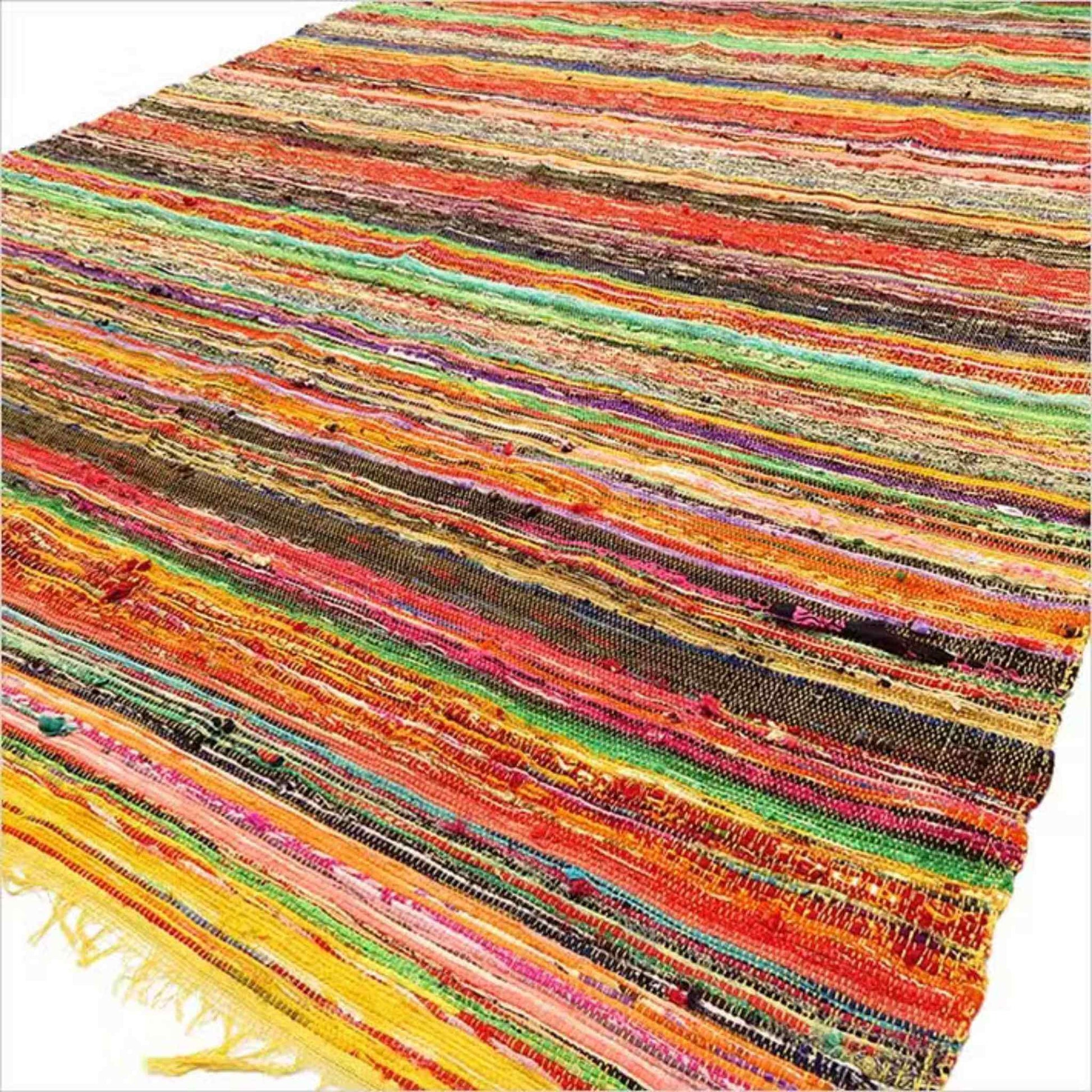 Angled view of a multicoloured striped Indian rag rug with strong red and orange tones.