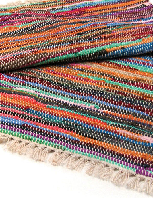 A folded multi-colour Indian rag rug with visible woven texture and tasselled edges.