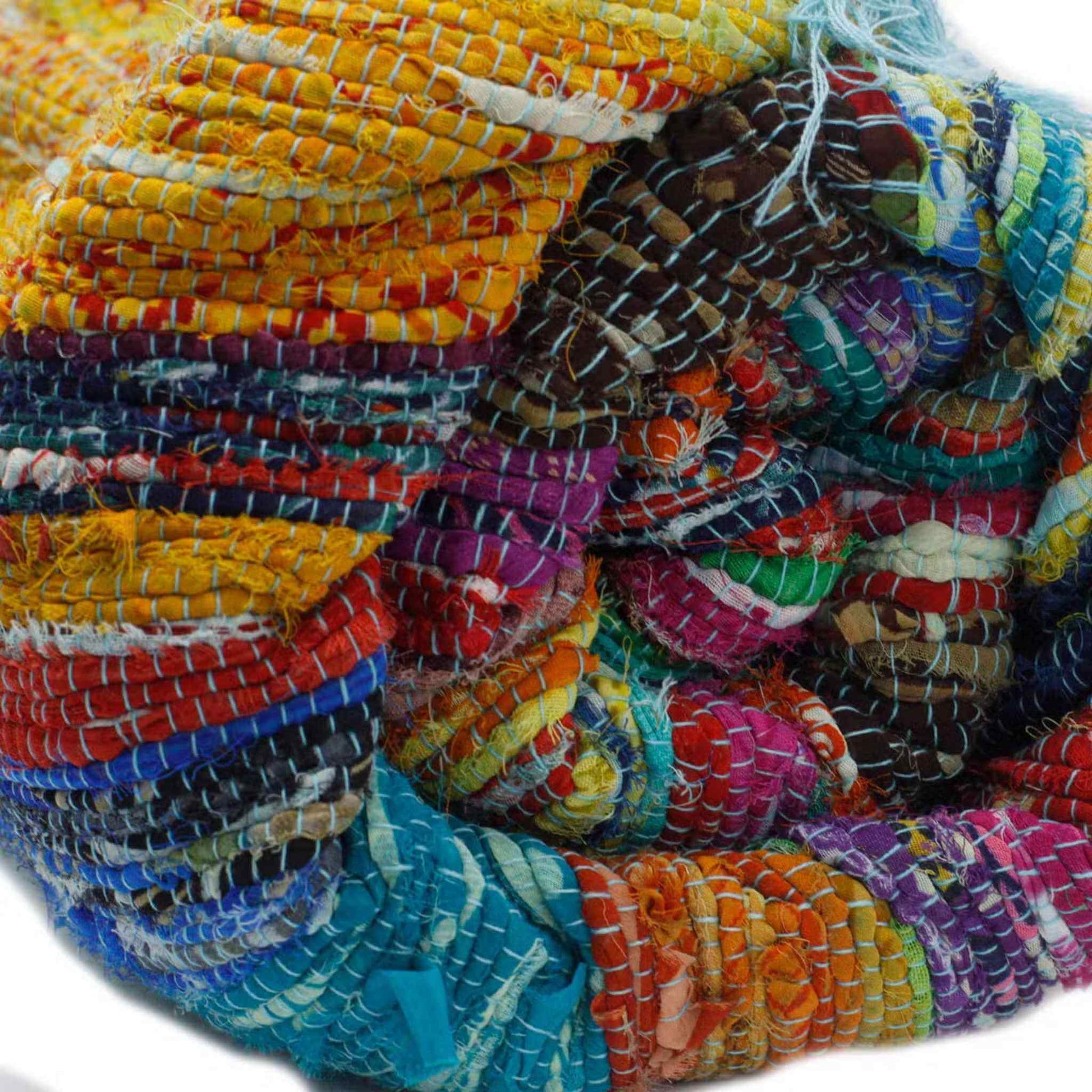Close view of a rolled multicoloured fabric rug, highlighting its handwoven pattern and recycled threads.