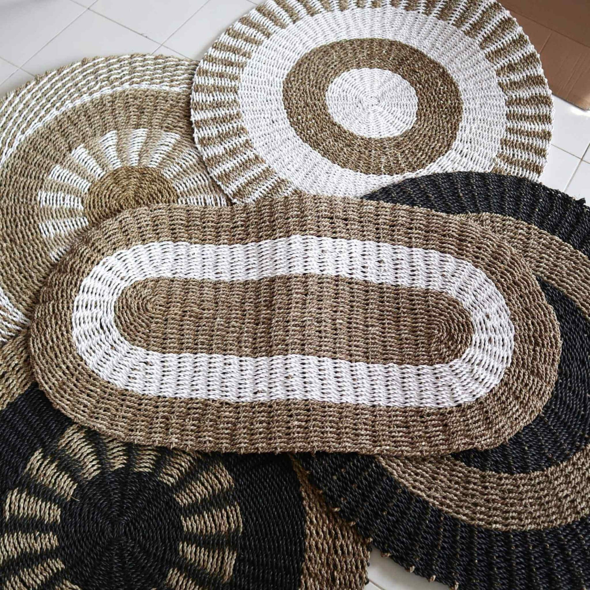 Hand-woven seagrass rugs in assorted oval and round shapes, white, tan, and black patterns.