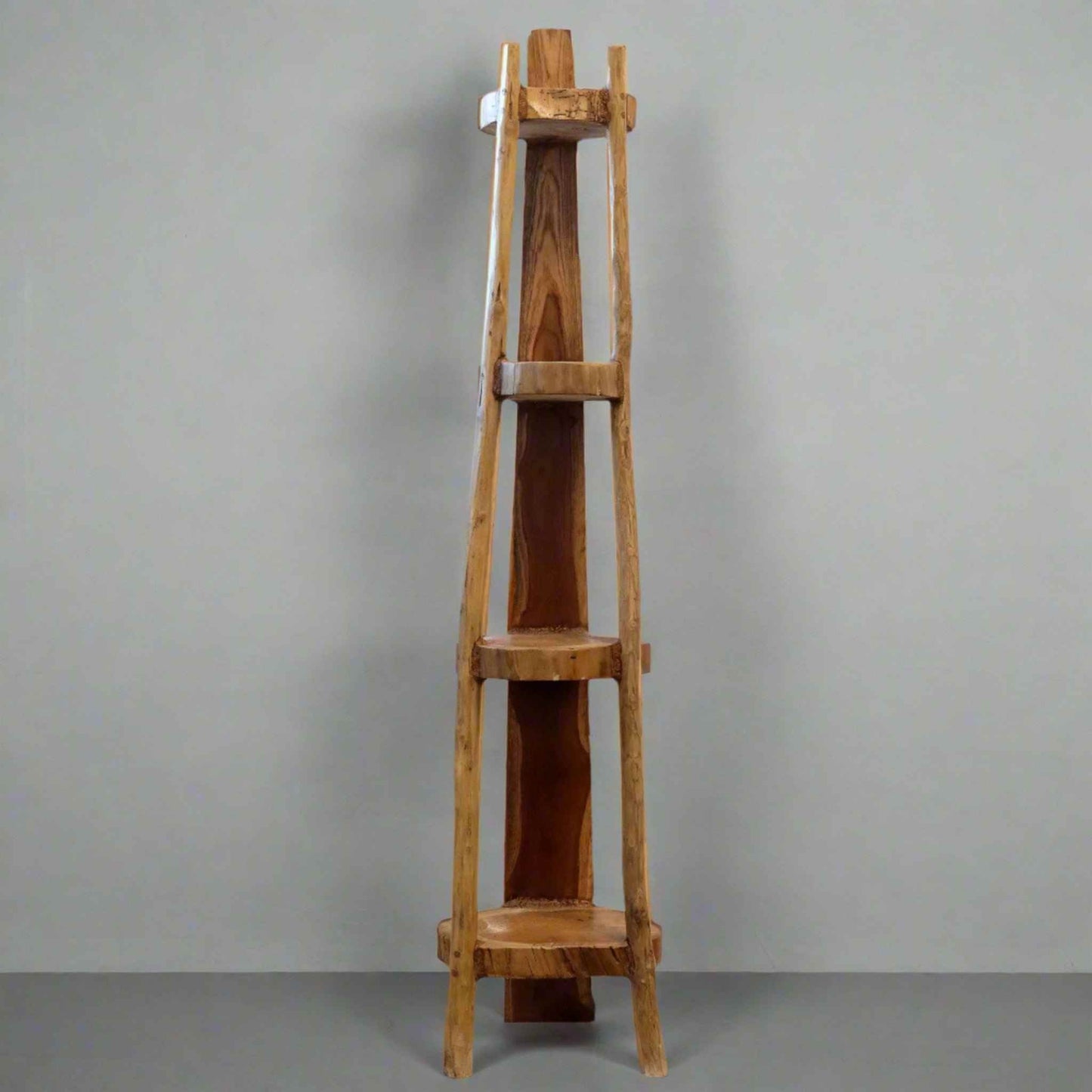 Natural teak 135cm corner unit with four fixed shelves, showing smooth wood grain and tapered shape against a grey wall.