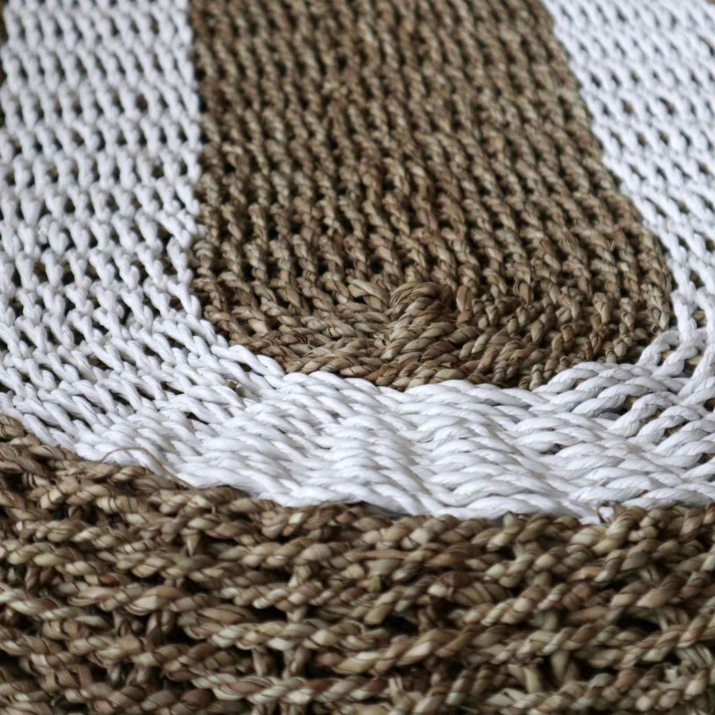 Close-up detail of hand-woven seagrass rug in white and tan showing natural texture.