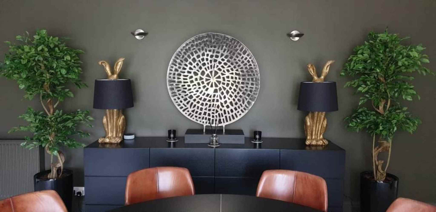 Two artificial twisted ficus trees flank a sideboard in a contemporary dining room.