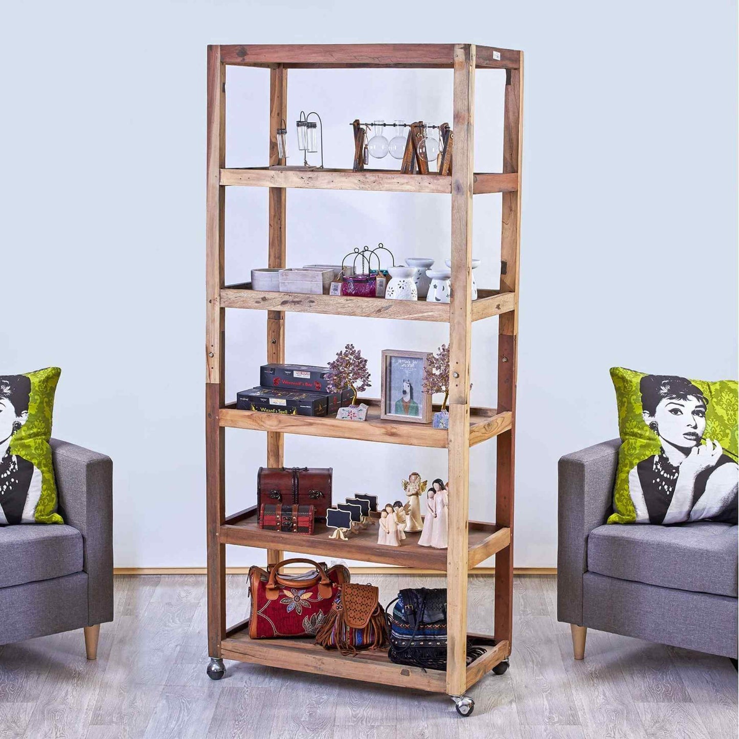 Hand-crafted wooden shelving unit in a natural finish, styled in a living room setting with armchairs and cushions.