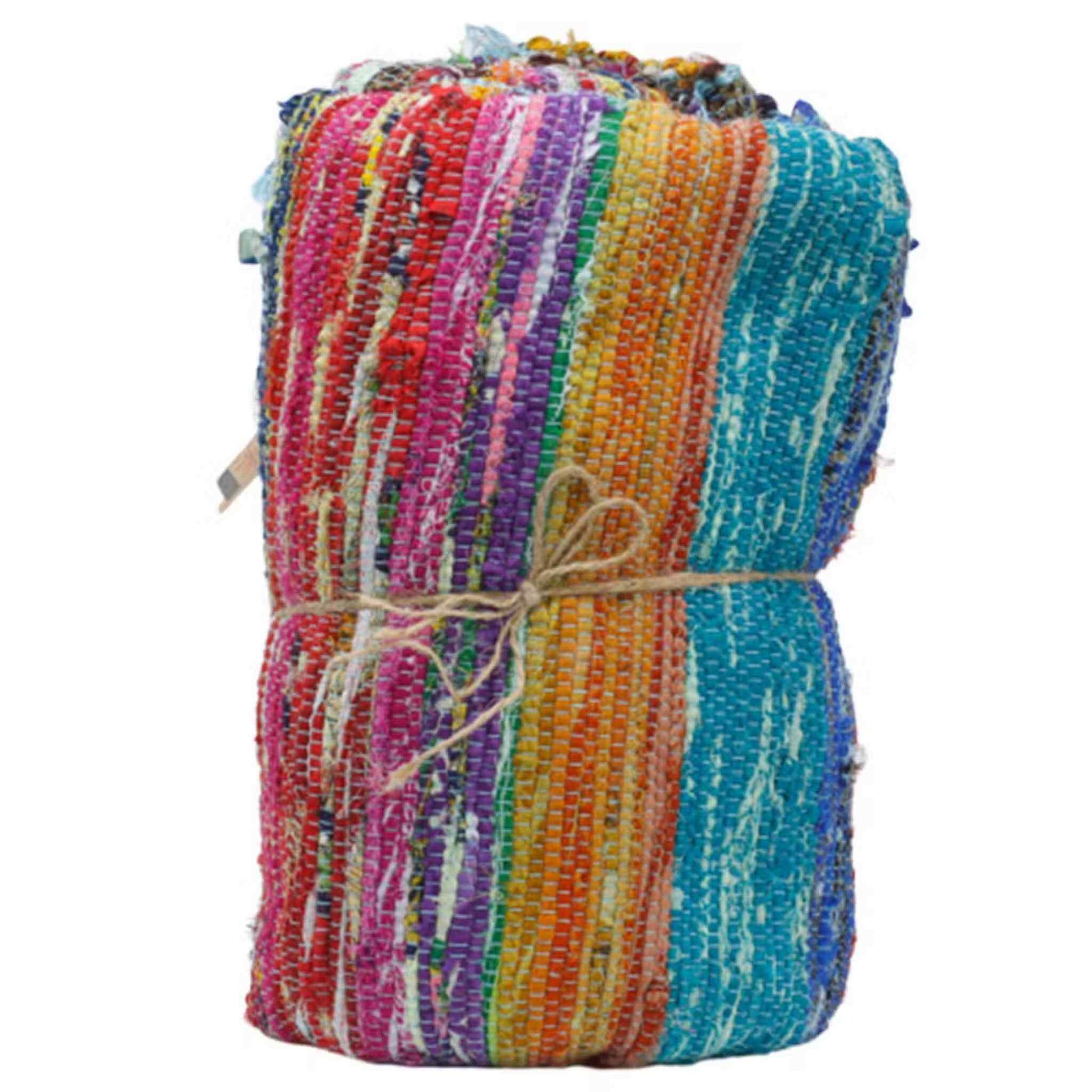 An Indian rag rug rolled and tied with rustic string, revealing vibrant stripes of blue, orange, and pink fabric.