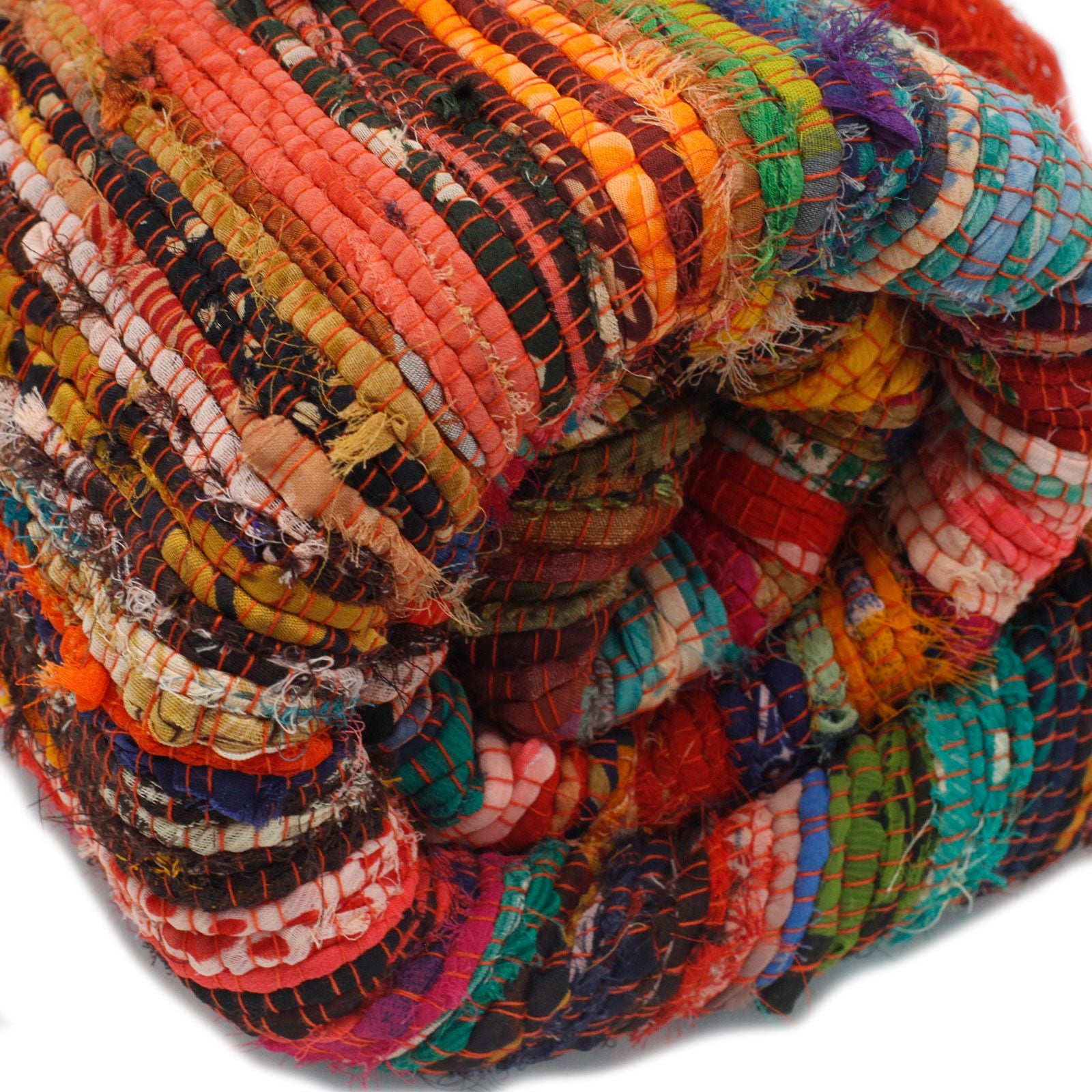 Close-up of rolled multicoloured orange rag rug showing soft cotton texture and frayed edges.