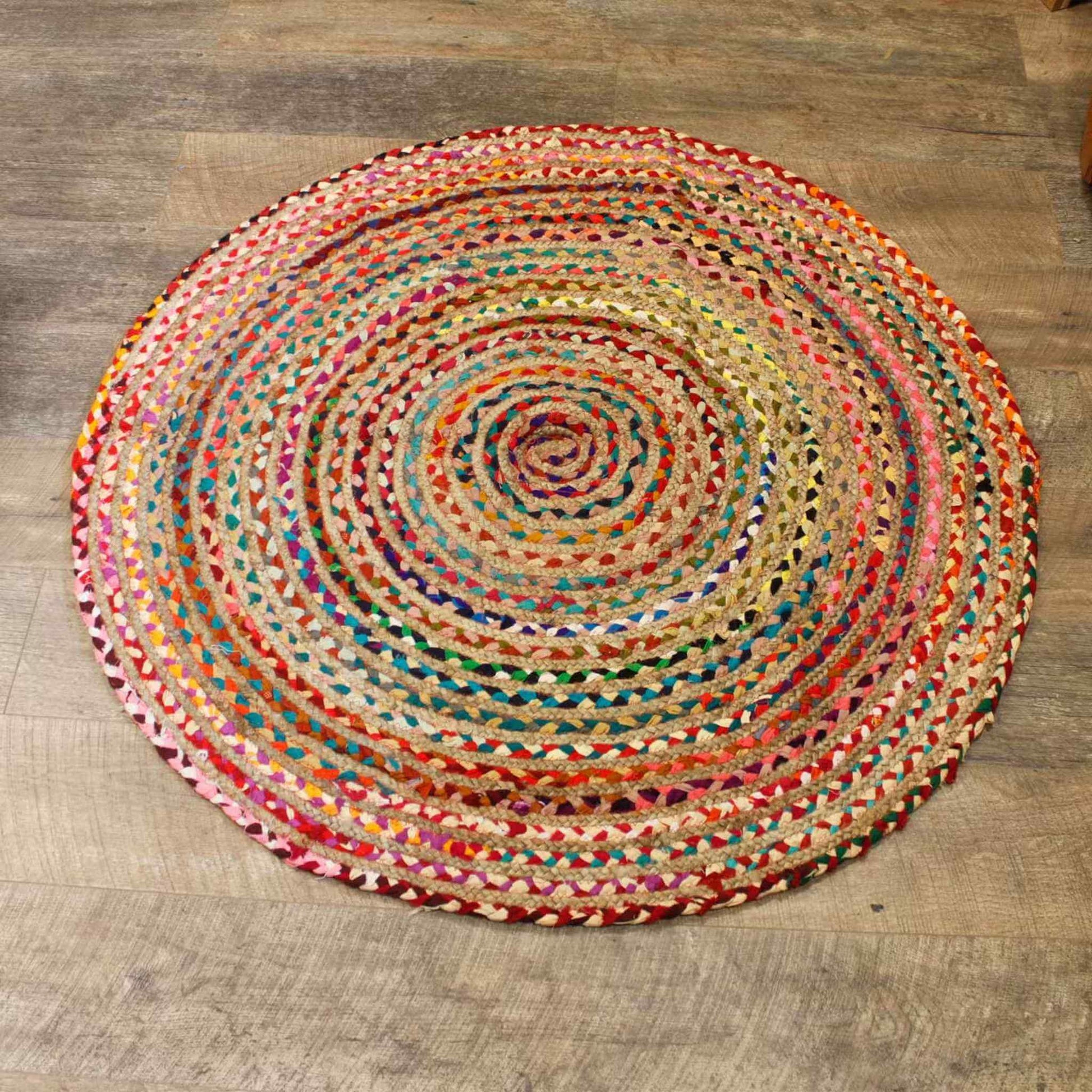 Round jute and recycled cotton rug, 120cm, with multicoloured braided design on a wooden floor.