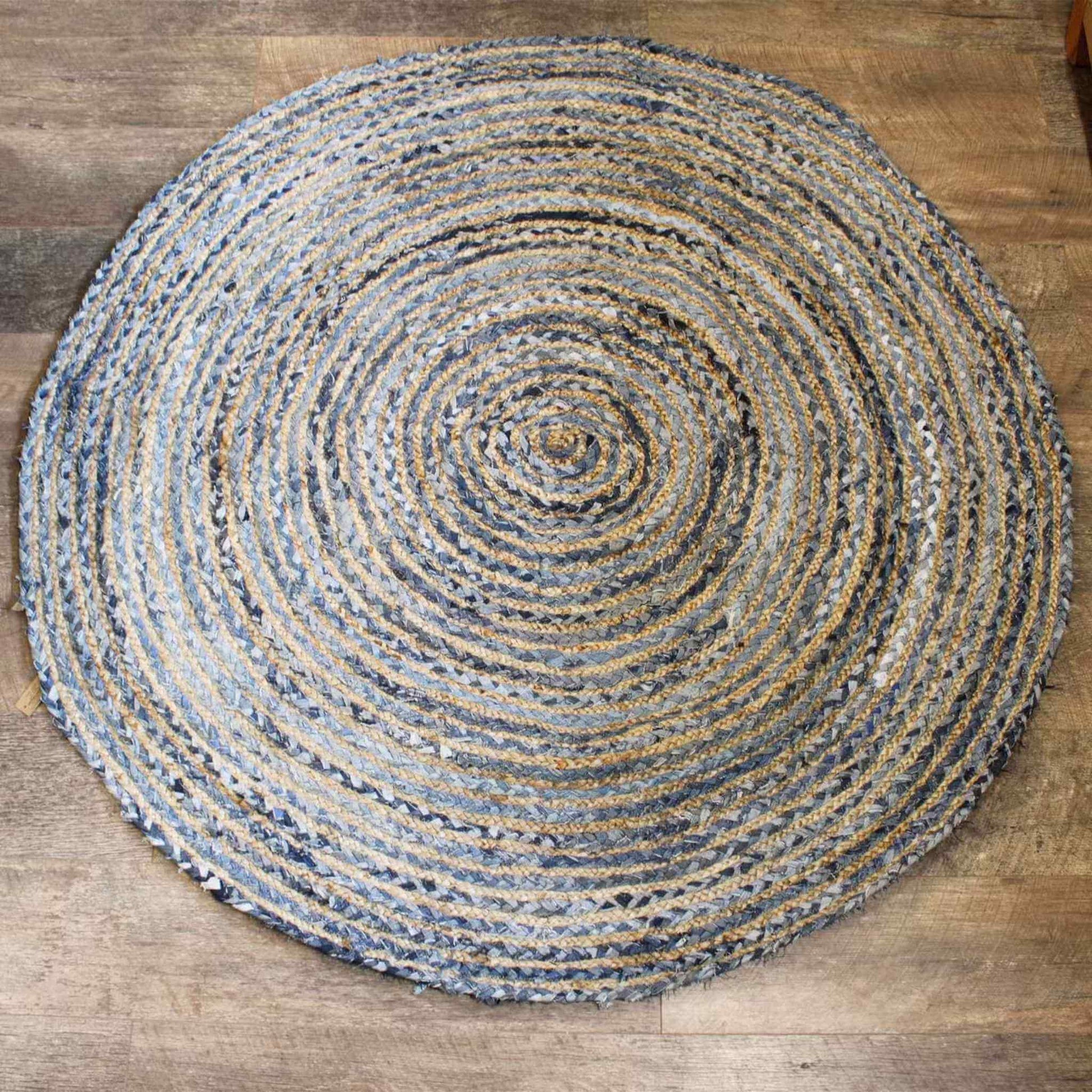 Overhead view of a 150cm round jute and recycled denim rug in a soft blue and tan braided pattern, placed on wooden flooring to show detail and texture.