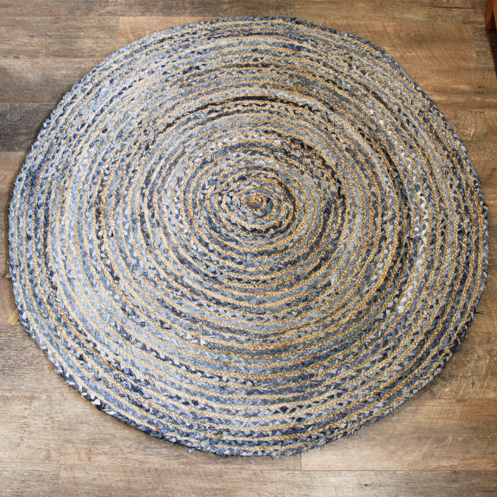 Top-down view of a 150cm round jute and recycled denim rug on a wooden floor.