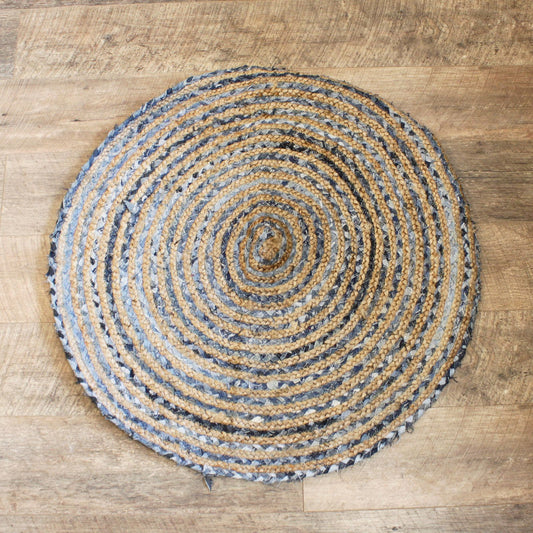 Round 90cm jute and denim rug with a braided spiral pattern on a wooden floor.