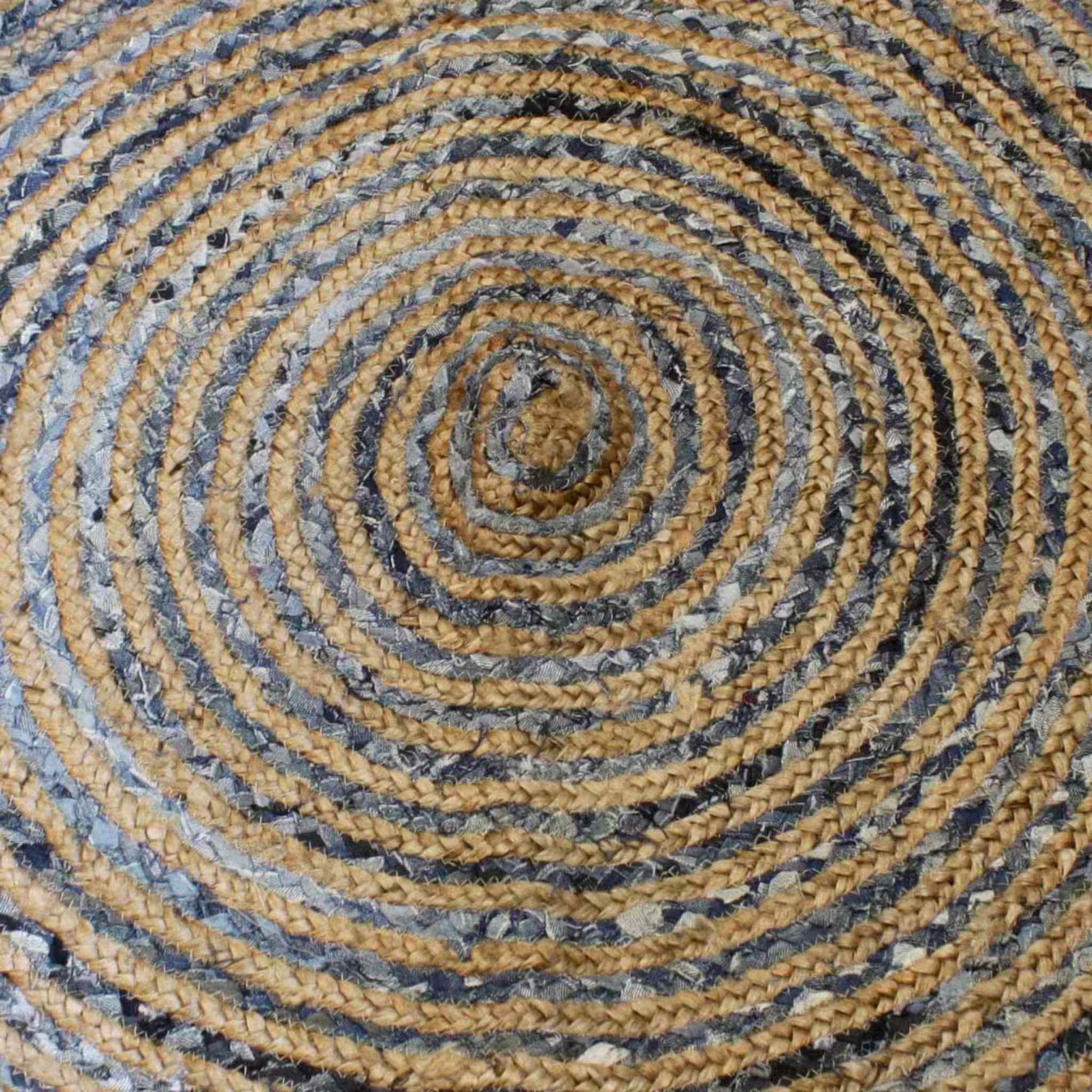 Close-up of round braided rug made from jute and recycled denim, showing detailed circular weave and natural texture.
