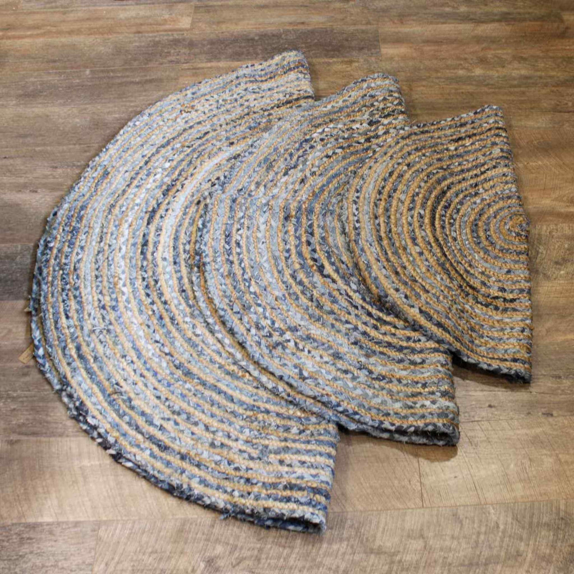 Set of three round jute and recycled denim rugs in 90cm, 120cm, and 150cm sizes, shown stacked on a wooden floor with natural beige and denim blue braiding.