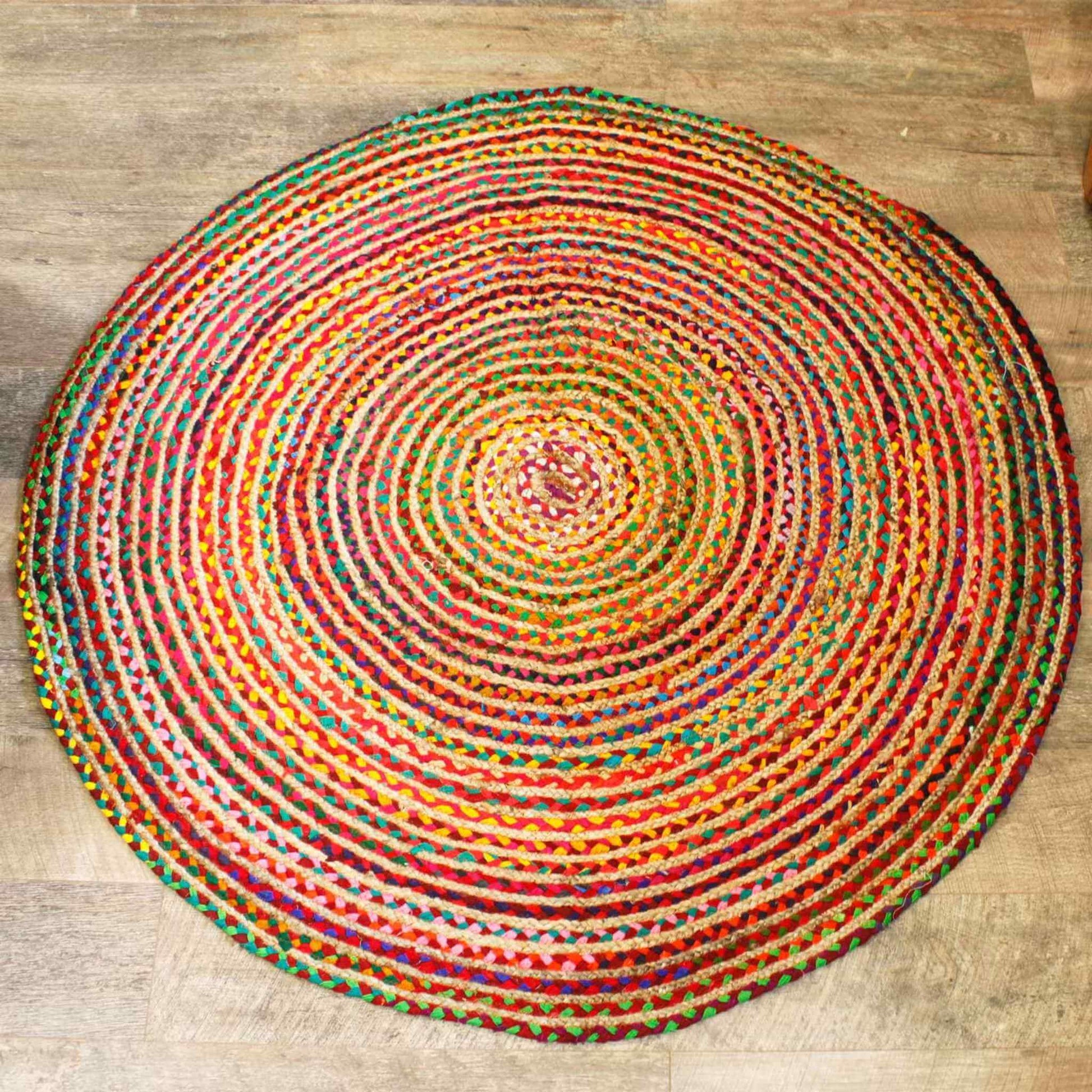 Round 150 cm jute and recycled cotton rug in a multicoloured braided pattern, shown on a wooden floor.