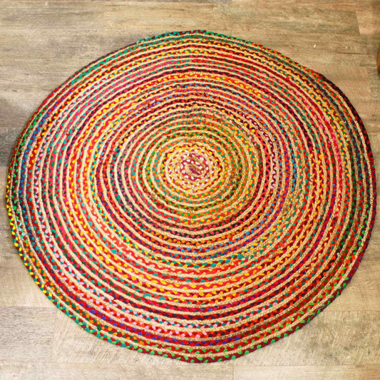 Round 150 cm jute and recycled cotton rug in a multicoloured braided pattern, shown on a wooden floor.