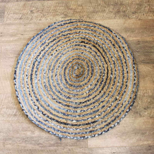 Overhead view of 90cm round jute and denim rug with alternating beige and blue braided rings, displayed on a wooden floor.