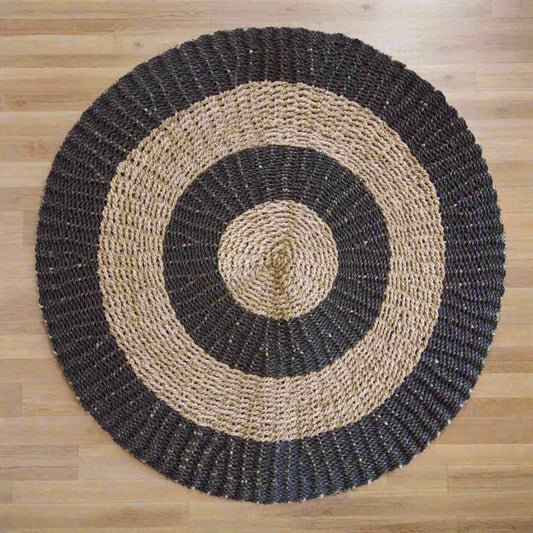 Full round seagrass rug in black and tan, 1 metre diameter, bold concentric circle pattern.