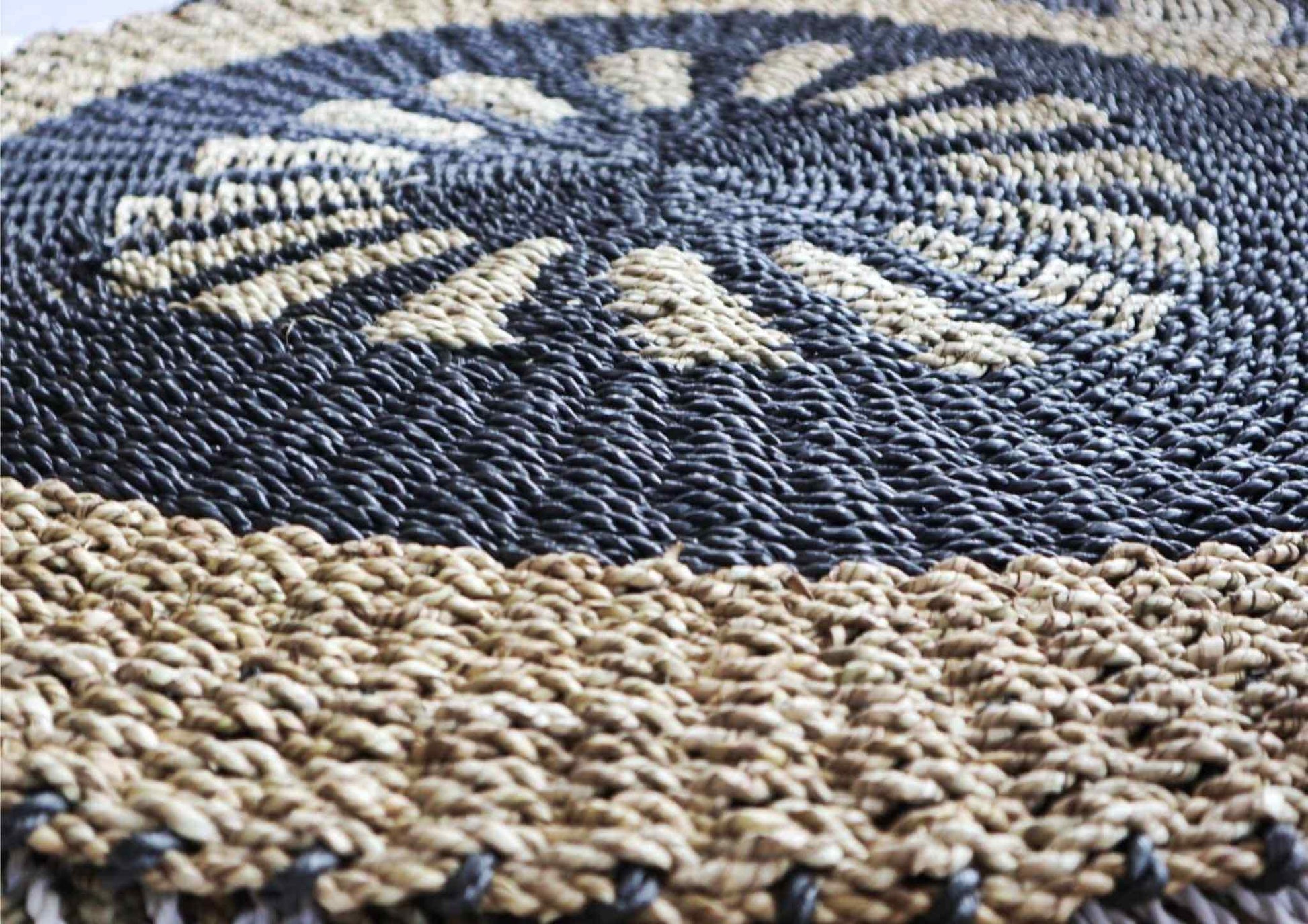 Close-up of a round seagrass rug with black and tan patterns, showcasing its textured weave.