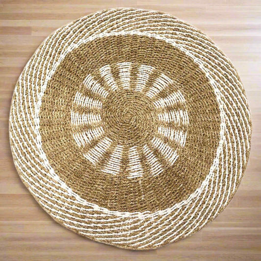 Round white and tan seagrass rug with sunburst design placed on light wood flooring, highlighting natural tones.