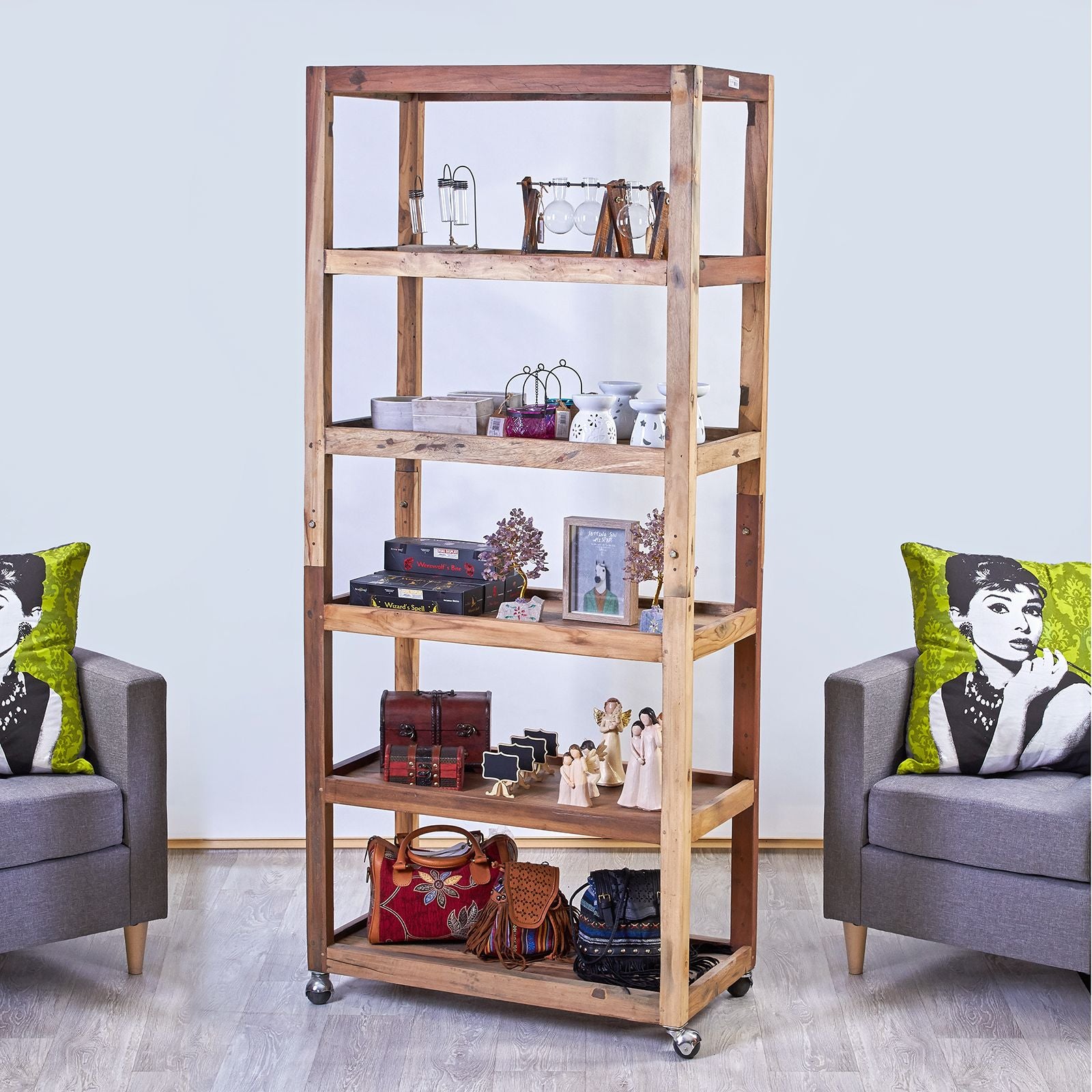 Rustic teak wood bookcase with six shelves, styled in a living room setting with armchairs and cushions.