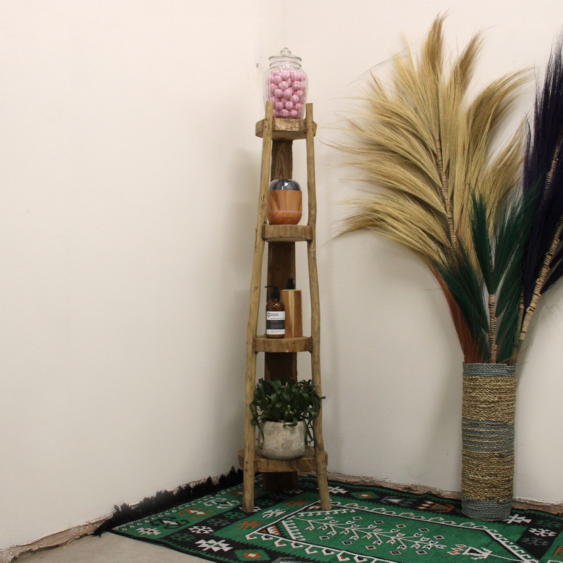 Styled teak corner shelf in a home setting with plants and decor items.